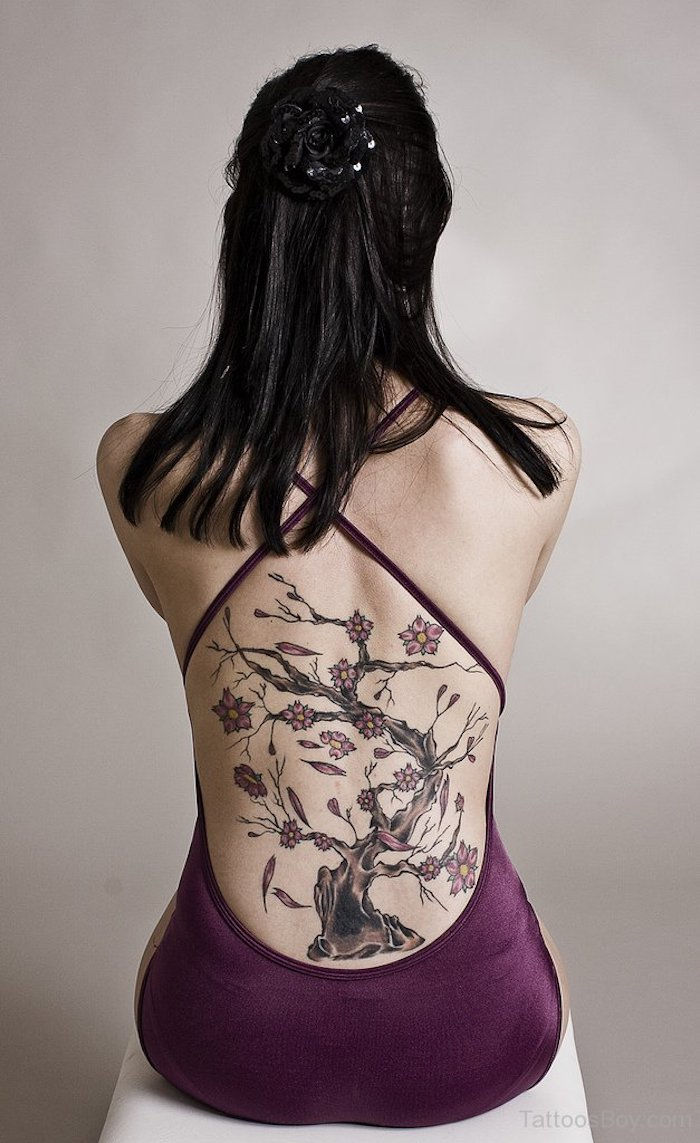 Vrouw met zwart steil haar, paarse jurk en kersenbloesem tattoo op de rug