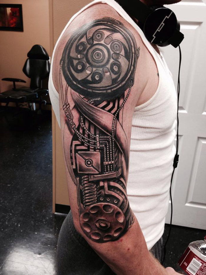 Omul cu tatuaj cu bratul superior cu piese de mașină, tatuaje pentru bărbați