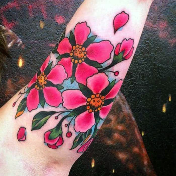Bloemtattoo op de bovenarm, tatoeage met roze kersenbloesems als motief