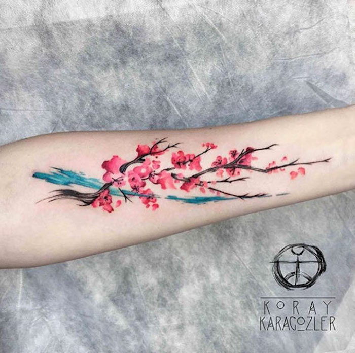 tattoo betekenis, gekleurde tatoeage op onderarm, tak met kersenbloesems