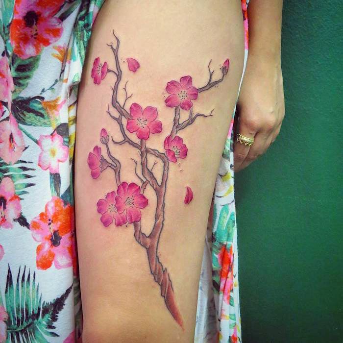 tatoeages met betekenis, takje met roze kersenbloesems op de dij