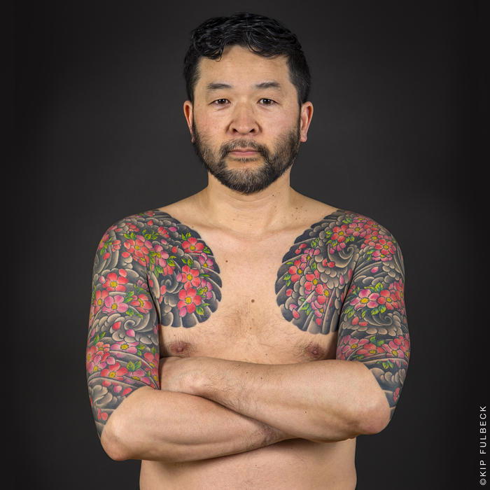 Japanse tatoeages, man met grote tatoeages met watergolven en kersenbloesems