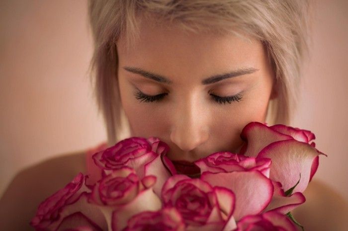 Ung vakker kvinne som holder bukett med rosa roser. Hun er veldig tilfredsstilt. Valentine's day or international women's day celebration.