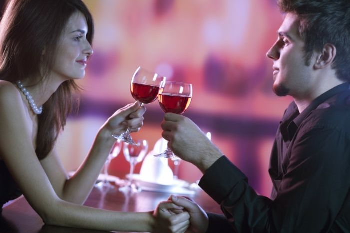 Ungt par deler et glass rødvin på restaurant, feirer eller på romantisk dato