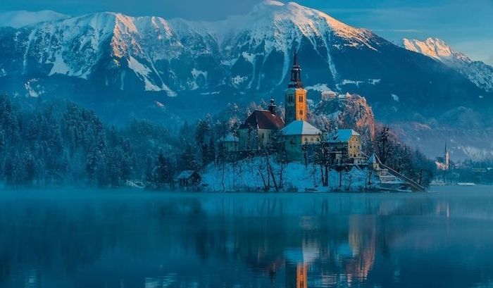 belle immagini invernali - lago e un'isola con una chiesa e piccole case - montagne invernali con neve e una foresta con alberi e. neve