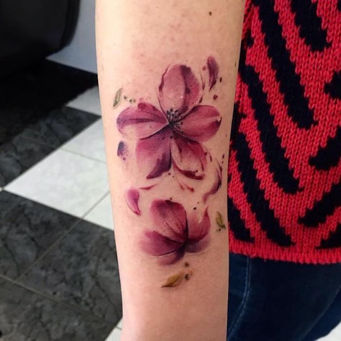 Bloemtatoegering op onderarm, roze bloemen met vliegende bladeren van bladeren
