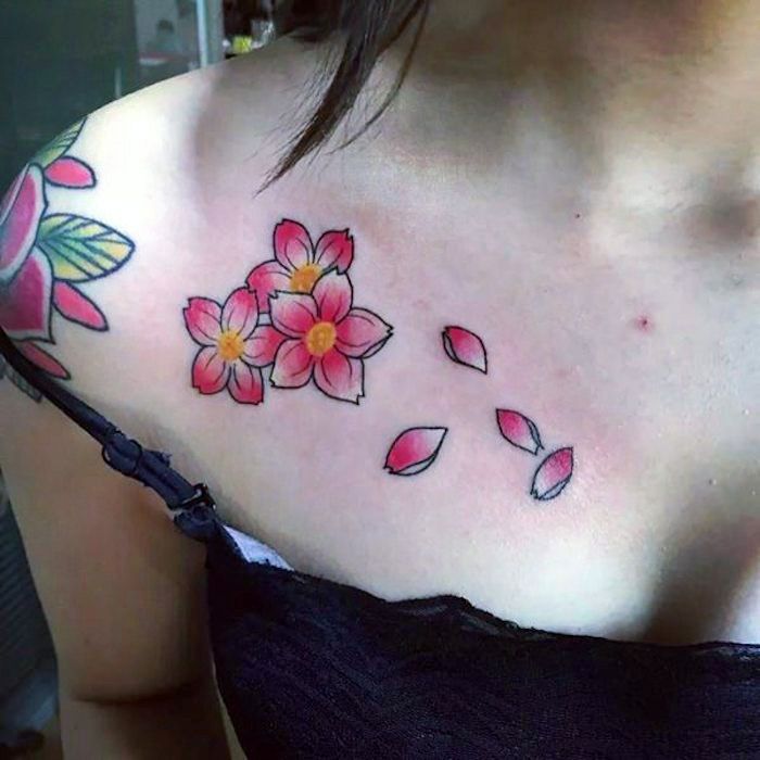 Vrouw met bloemtatoegering op schouder, roze kersenbloesems met vliegende bloemblaadjes