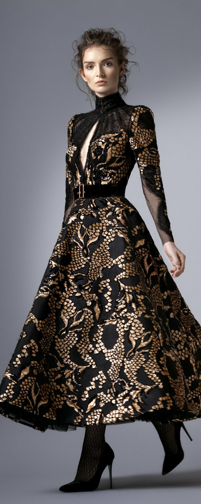 elegant dammodell - lång klänning i svart och guldfärg med Semtgürtel med gyllene stängning, Pollokragen och öppen vid bröstet, avslappnad updo för lockigt hår, fisknetströjor och svarta hälskor