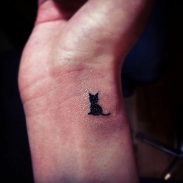 pomysł na tatuaż małego czarnego kota na nadgarstku - tutaj jest mały kot z czarnym kutasem