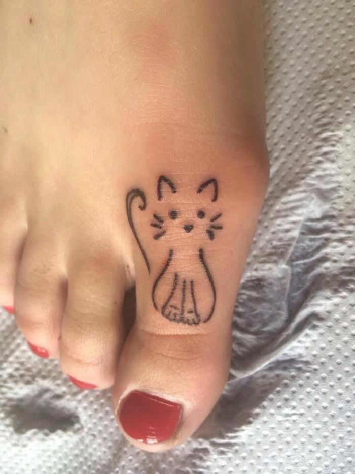 pomysł na tatuaż dla małych kotów - tutaj jest duży palec u nogi z czerwonym lakierem do paznokci i małym czarnym kotem