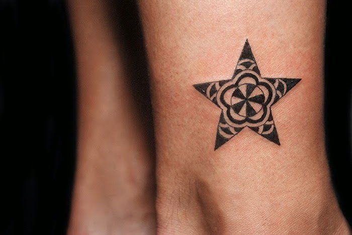 piccolo tatuaggio nero - una gamba con un tatuaggio con una piccola stella nera