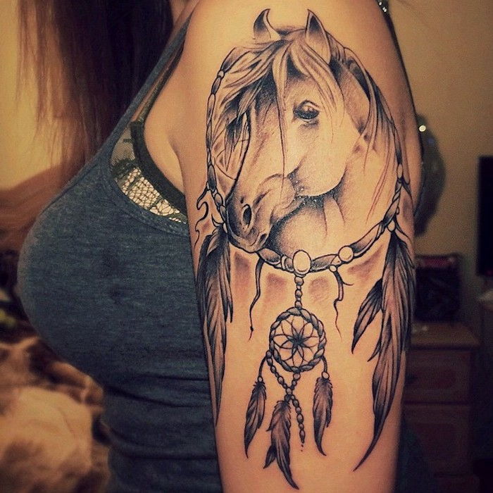 Aruncați o privire la această idee pentru tatuaj pentru o femeie pe umăr - un tatuaj cu un cal și un captator de vis cu pene lungi