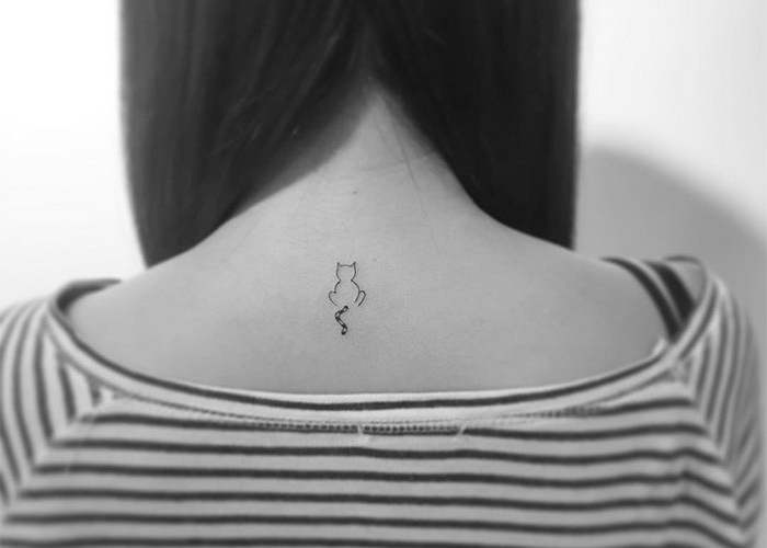tatuaż dla kobiet - oto mały czarny tatuaż z kotem na plecach i kobietą w pasiastą bluzkę