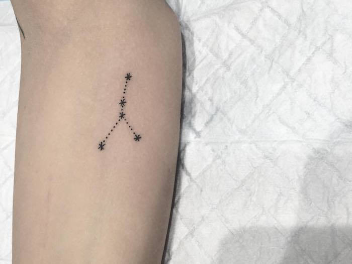 piccolo tatuaggio nero con una stella nera con piccole stelle nere - una mano con tatuaggio a stella