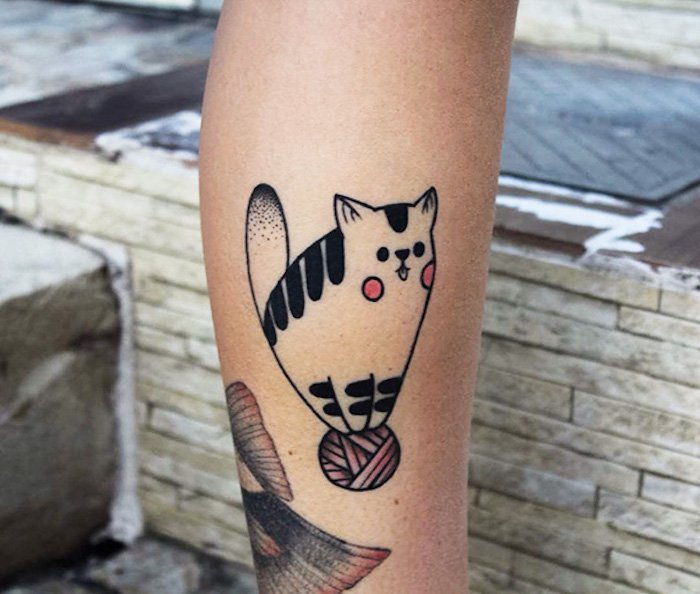 pomysł na tatuaż kota na nodze - tu jest czerwona kula z włóczki i mały kot z czerwonymi policzkami