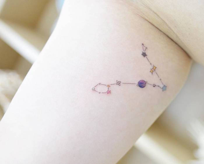 Mano con un tatuaggio con una stella con un piccolo pianeta viola e piccole stelle blu e gialle