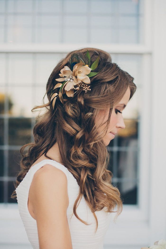 capelli ricci, un fiore nei capelli con foglie verdi innocenti look acconciature da sposa