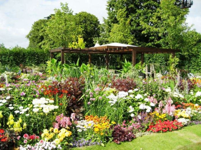 ľahko udržiavaná záhrada s mnohými rôznymi kvetmi a drevenou pergolou