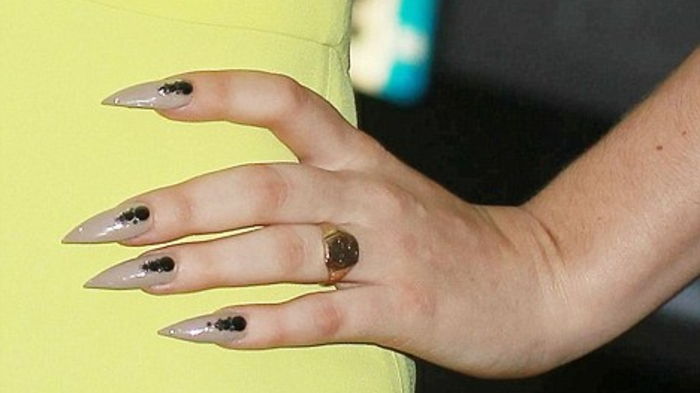 Spetsna naglarna av Lady Gaga beige färg av naglarna svarta och gyllene ringgula klänningen