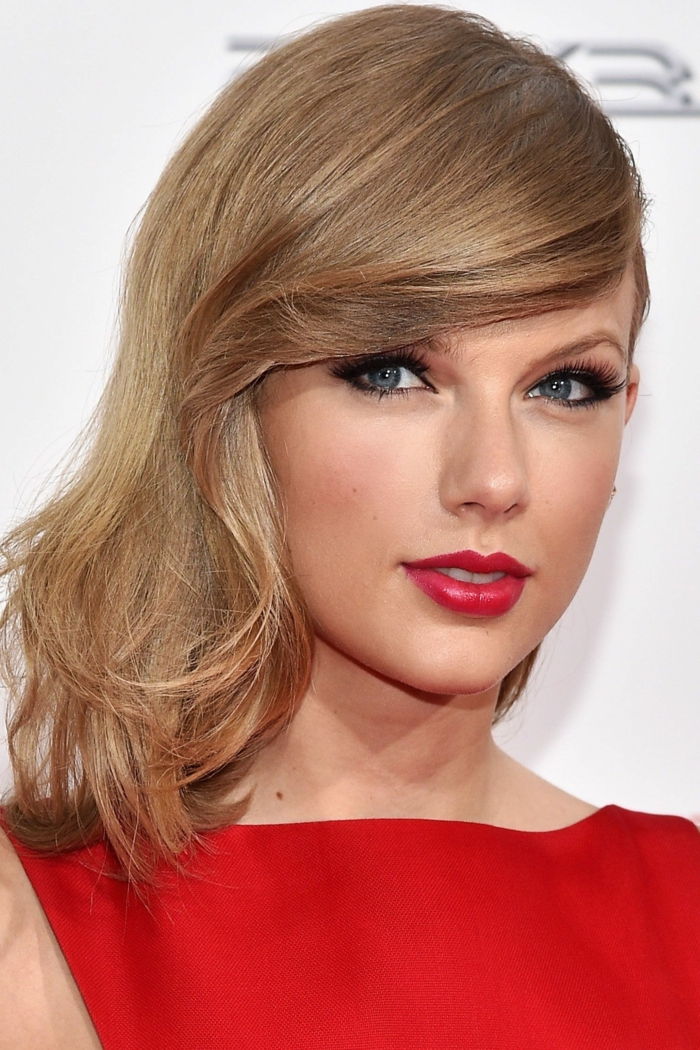 Taylor Swift i rødt, lysebrunt hår og blå øyne, lyse røde lepper og lyse rouge