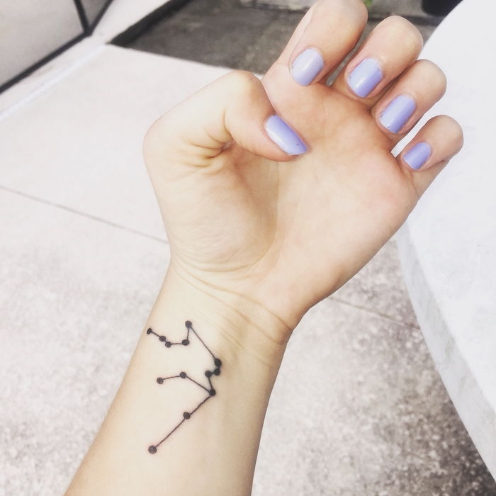 tattoo star for women - una mano con smalto viola e un tatuaggio con una stella nera sul polso