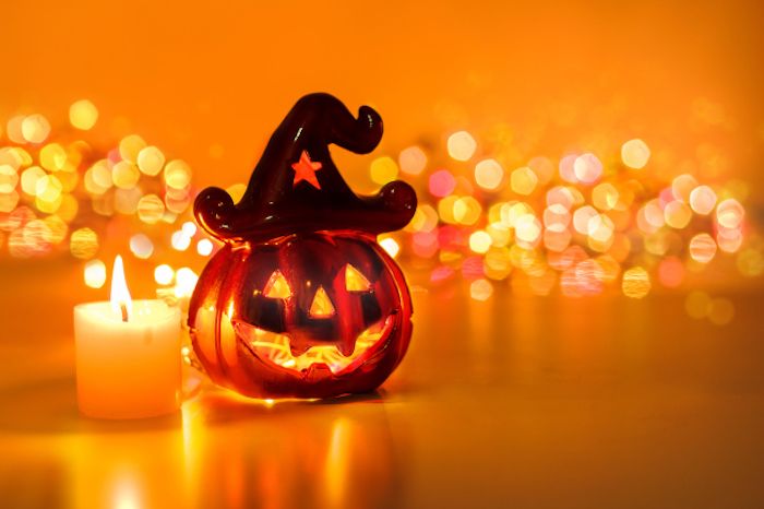en glasfigur bredvid ett ljus och lysande ljus i bakgrunden - Halloween bakgrund