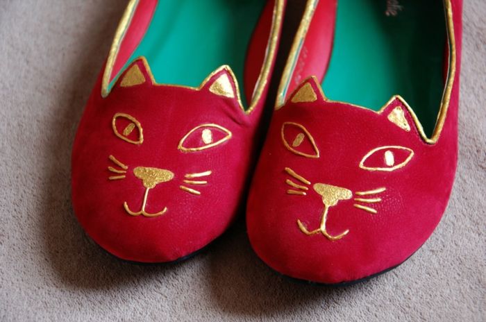 pantofi roșii coase cu un ornament de aur ca o față de pisică