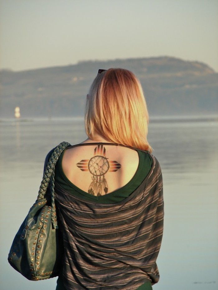 O idee pentru un tatuaj mic, cu captura de vis și cruce pe spatele unei tinere femei