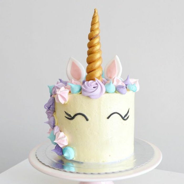 Tukaj je bela unicorn torta z vijoličastimi cvetovi