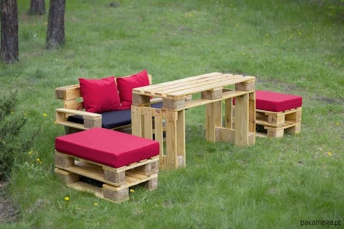 uma mesa, duas cadeirinhas feitas de hilz e um banco de jardim feito de europaletes e com almofadas vermelhas