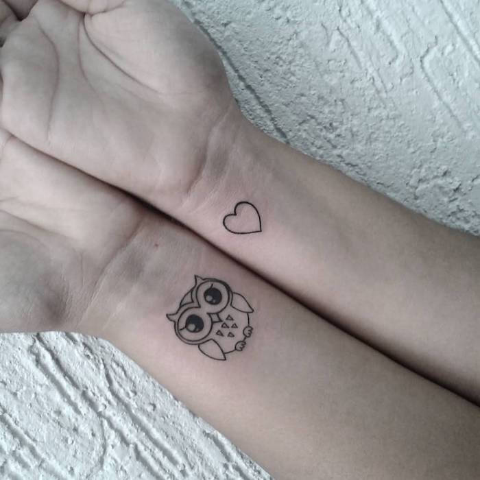 Qui ci sono due mini tatuaggi neri con un gufo e un piccolo cuore al polso