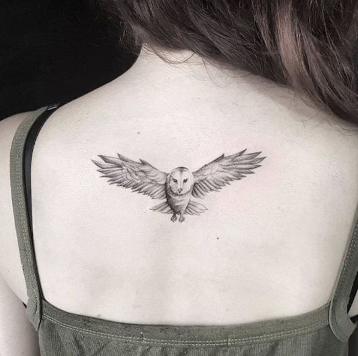 piccolo gufo volante - idea per un tatuaggio gufo sul retro di una giovane donna