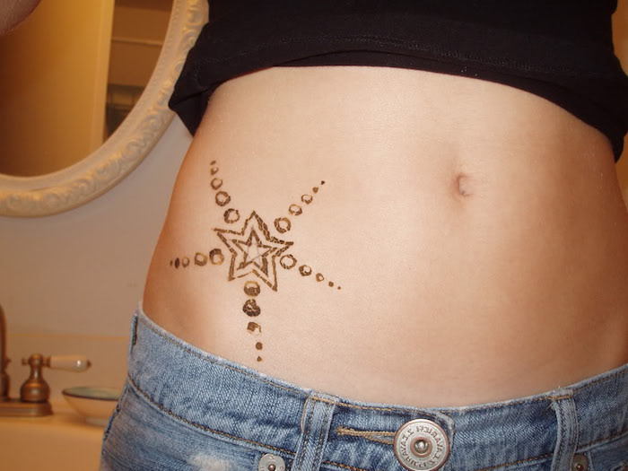 Una giovane donna con un tatuaggio nero con una piccola stella nera e pantaloni blu - idea sul tema della stella del tatuaggio
