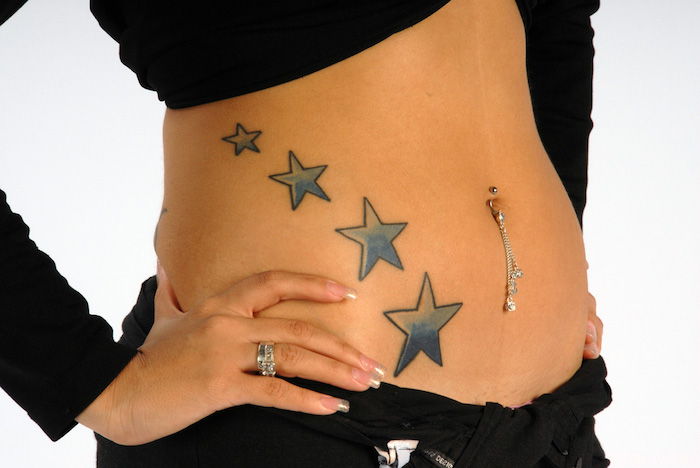 tatuaggio con quattro grandi stelle blu - una giovane donna con tatuaggio stellato - mano con smalto e lotta per il vino bianco
