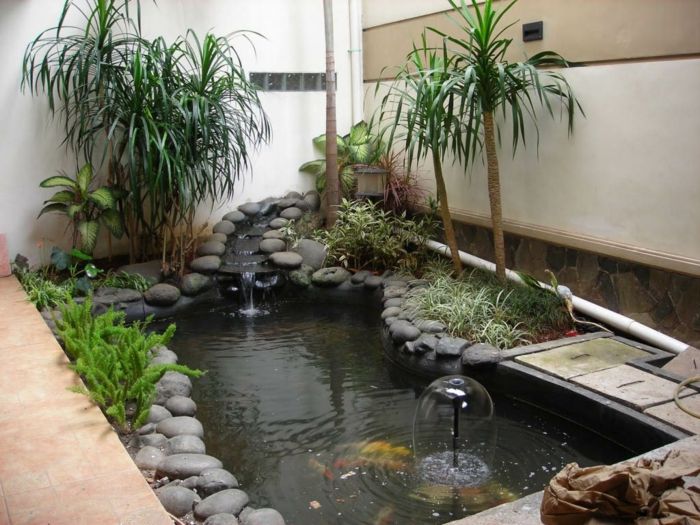 krásny vodný prvok s mnohými šedými kameňmi a exotickými palmami - príklady záhradného dizajnu