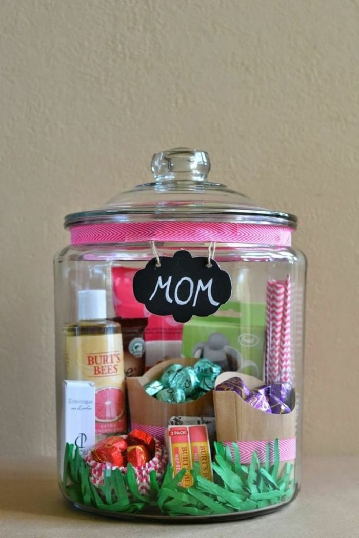 um frasco de pedreiro cheio de doces e cosméticos com fita rosa e uma tabela de presentes para o dia das mães
