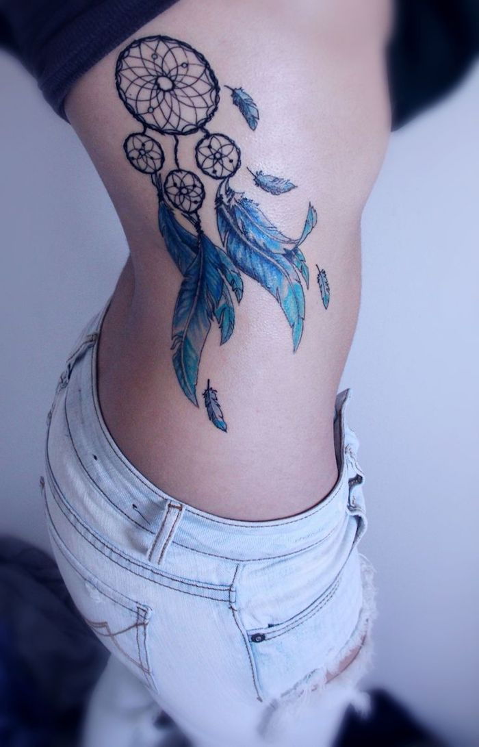 Aruncați o privire la această idee pentru un tatuaj foarte frumos, cu un captator de vis cu pene albastre lungi - tatuaj pentru o femeie