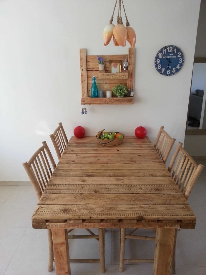 drevený stôl, drevené stoličky a samolepiaca polica z palet a dreva s kvetmi, obraz a modrá fľaša