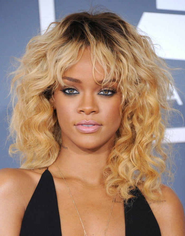 Rihanna s pony účes, tmavo blond kudrlinky, matné pery a čierna riasenka, čierne večerné šaty