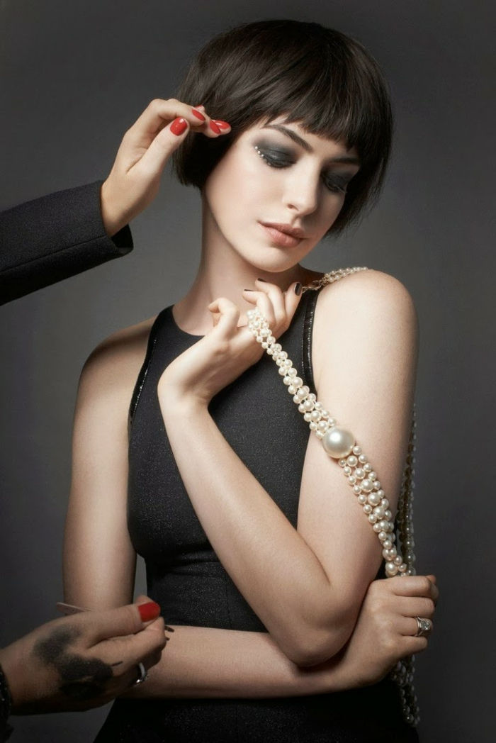 Anne Hathaway s krátkym účesom poníkov, matnými perami a dymovými očami, čiernymi šatami, perlami
