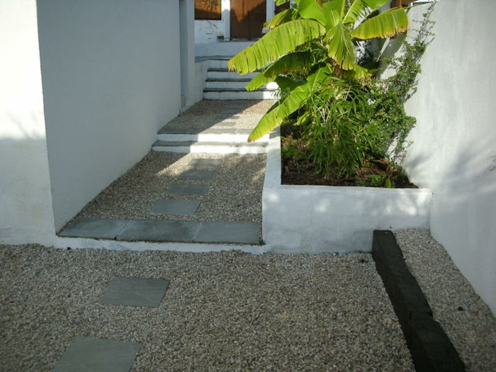 Kamenistá podlaha a kamene na ceste, zelené rastliny - moderný predný dvor