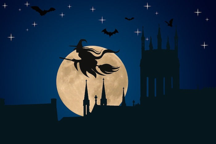 Halloween bakgrund - en häxa på kvastet flyger över en medeltida stad