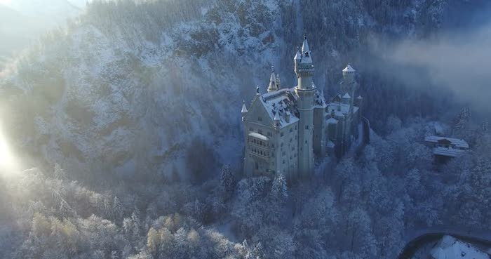un castello con torri nel tramonto - una foresta con molti alberi con neve e nuvole bianche