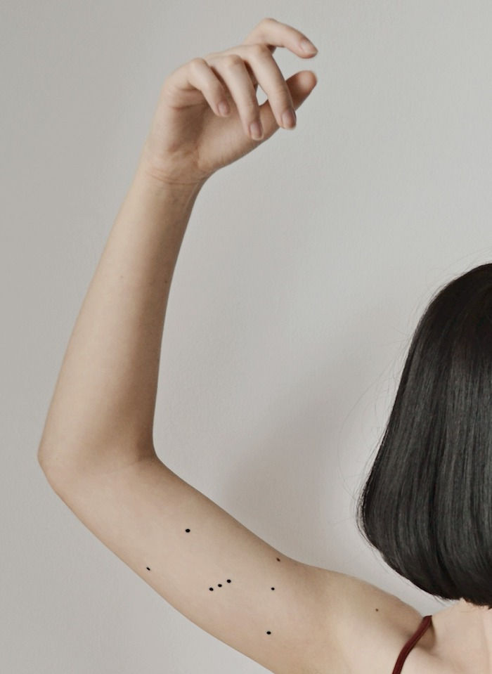 giovane donna e un tatuaggio winzattoo con un'immagine stella nera con piccole stelle nere - una mano con tatuaggio stella