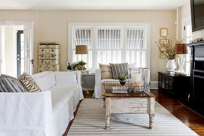 Shabby elegantna dnevna soba v pastelnih barvah, miza s sledmi uporabe, kavč v beli barvi