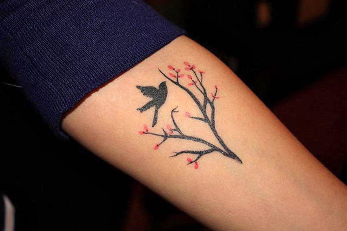 symbool van kracht en vrijheid, kleine tatoeage met vogelmotief, tak met bloemen