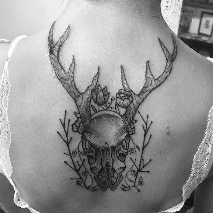 dövme kafatası - büyük boynuzlu ve iki küçük çiçekli bir geyik kafatası ile siyah dövme olan bir kadın