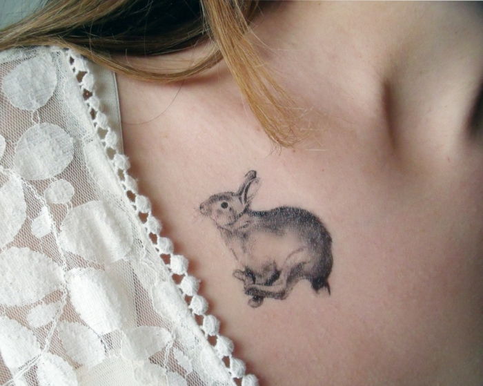 Tatuagens motivo pequeno coelhinho pulando no ombro de uma mulher loira cabelo rendas blusa decoração