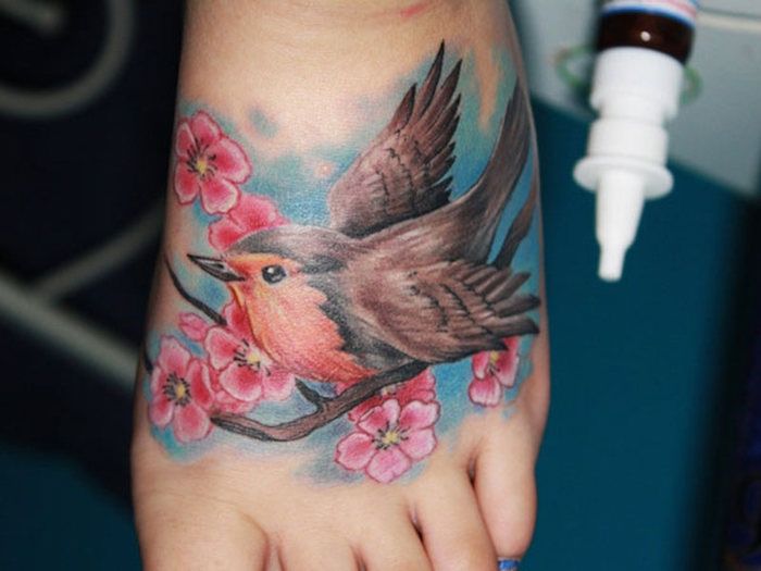 tatoeage kersenbloesems, bouwvogel op tak, gekleurde tatoeage op de voet
