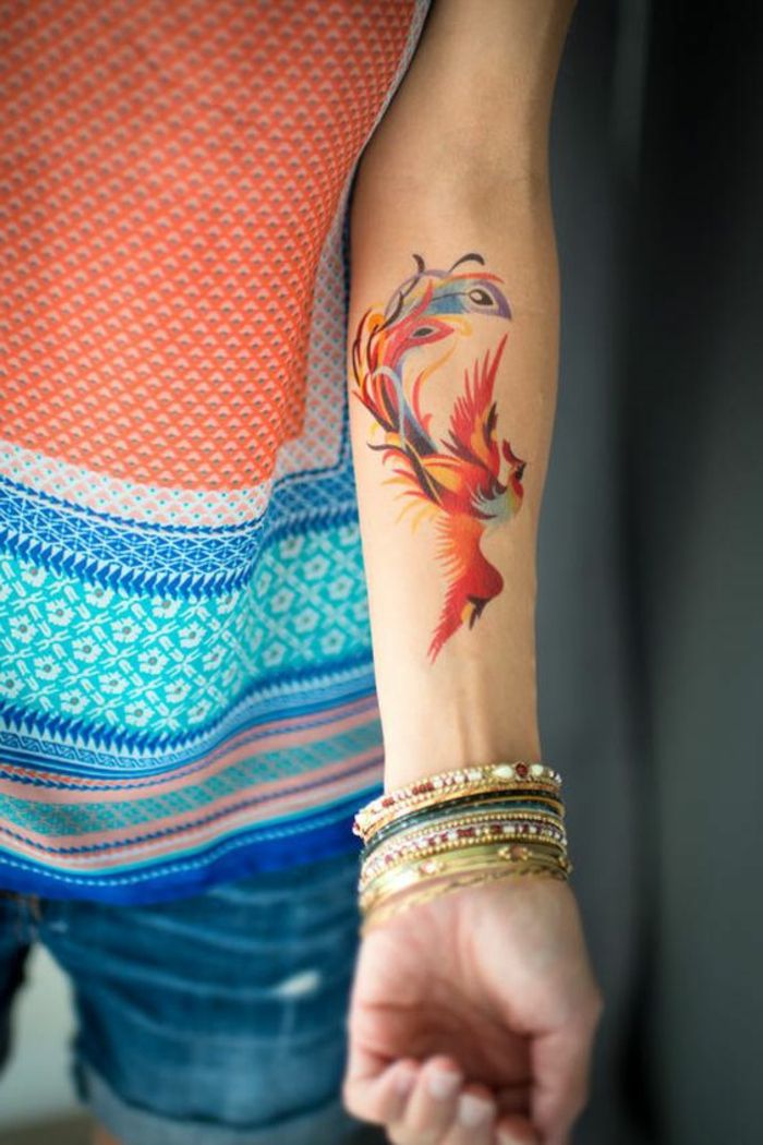 pequenas idéias de tatuagem phönih pássaro pintado no braço com cores coloridas muitas pulseiras coloridas